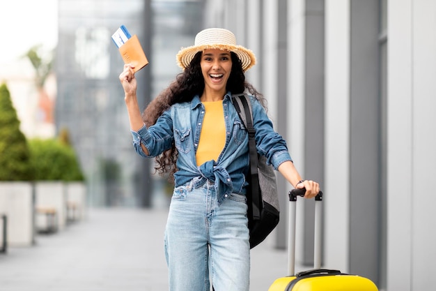 Excited young woman going vacation alone showing passport