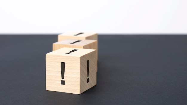 Exclamation mark sign on a wooden block on a black background with copy space