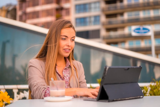 Executive blonde woman businesswoman having a decaffeinated breakfast from cafe with the tablet