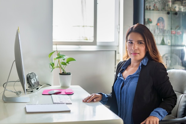 Executive woman in her office with large windows where the light enters.