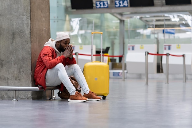 Exhausted african man on a long night connection at airport waiting for a plane sitting in terminal