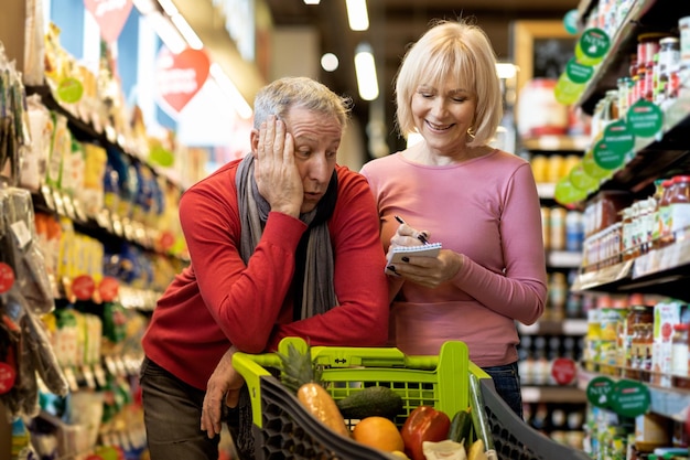 Exhausted husband shopping with his wife at supermarket