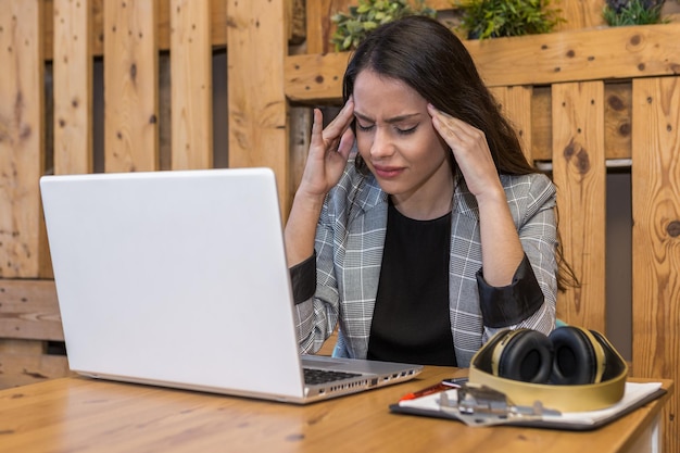 Exhausted woman working on laptop in cafe