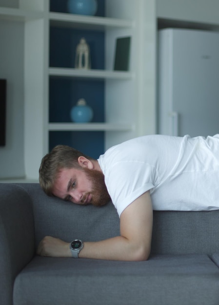 Exhausted young man fell asleep on comfortable couch in modern living room having no energy after