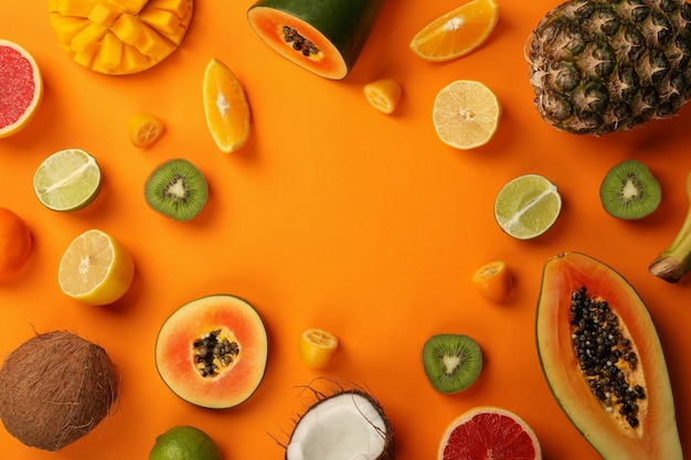 Exotic fruits set on orange background, space for text.