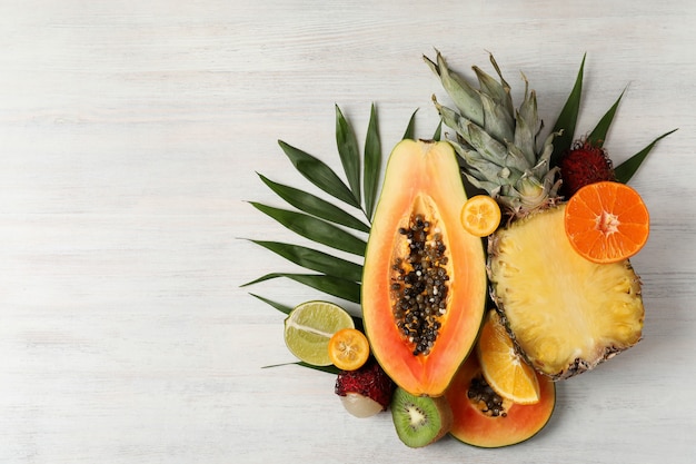 Exotic fruits on white wooden background, space for text.