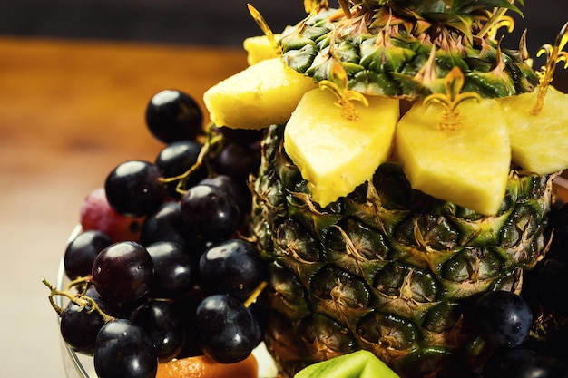 Exotic tasty fruits on a plate such as pineapple grapes oranges and kiwi