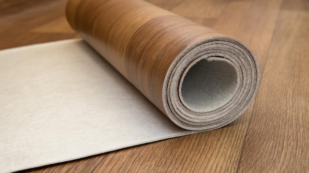 An expanded roll of brown linoleum. Close-up side view. Linoleum with wood structure