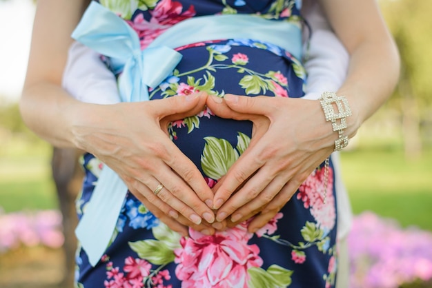 Expectant parents hold their hands on a pregnant woman's stomach