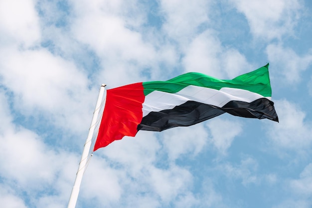 Experience a sense of patriotism and unity as the UAE flag stands tall and strong against the bright sunny skies of the nation