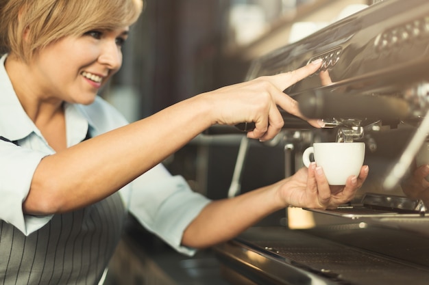 Experienced barista making coffee in professional coffee machine. Woman preparing beverage. Focus on hands. Small business and professional coffee brewing concept