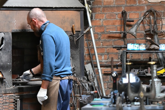 An experienced blacksmith works with open fire