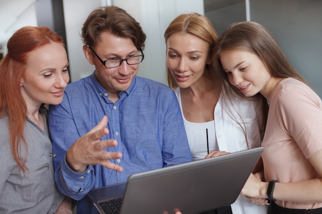 Experienced businessman showing something on his laptop to female colleagues