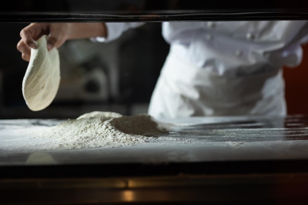 Photo experienced chef professional chef prepares the dough with flour to make pizza or pasta italian food