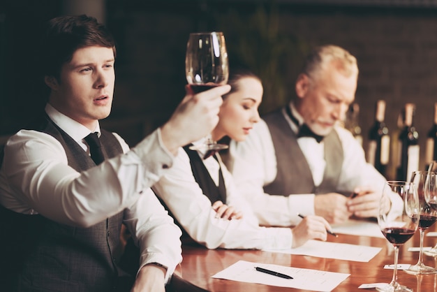 Experienced sommelier looks at sediment of wine in glass.