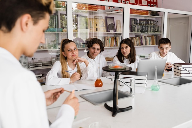 Experiment with fire School chemistry teacher shows children experiments in the laboratory Education concept Group lesson of classmates at chemistry lesson