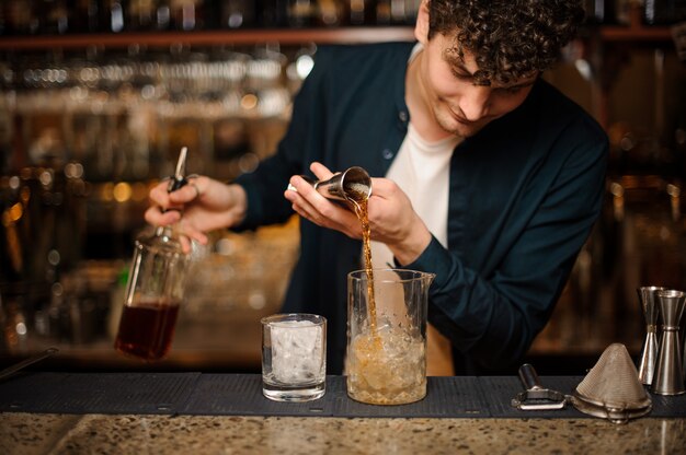 Expert barman is making cocktail at night club