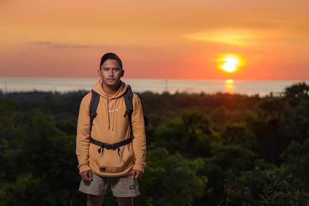 explorer man wearing backpack at sunset against beautiful evening sky