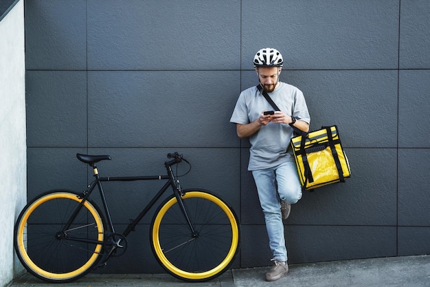 Express food delivery courier with insulated bag looking at phone