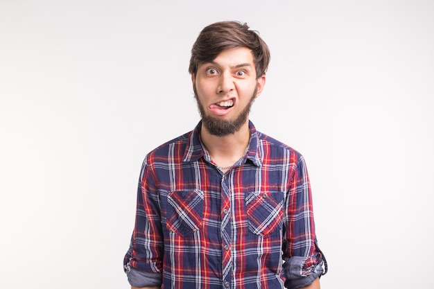 Expression and gesture concept -Young man sticks his tongue out isolated on white background