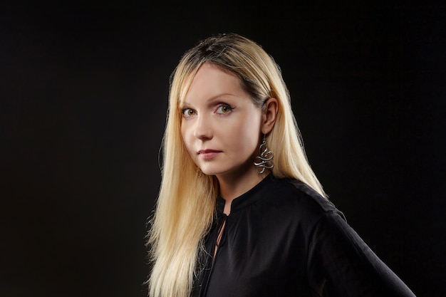 Expressive portrait of an attractive blonde in a photo studio on a black background.