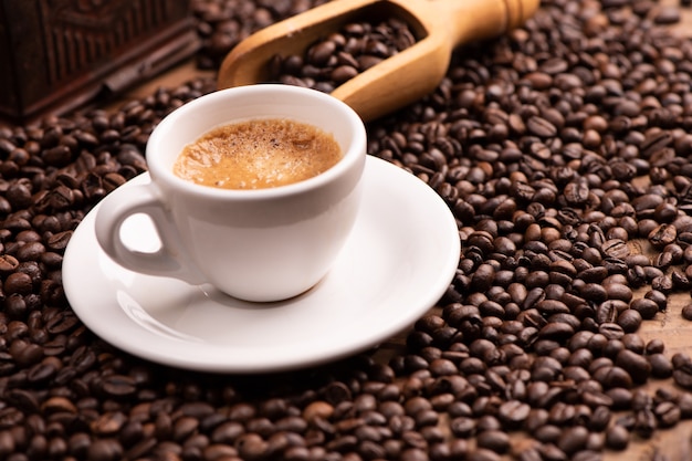 Expresso coffee cup close-up over dark roasted coffee beans