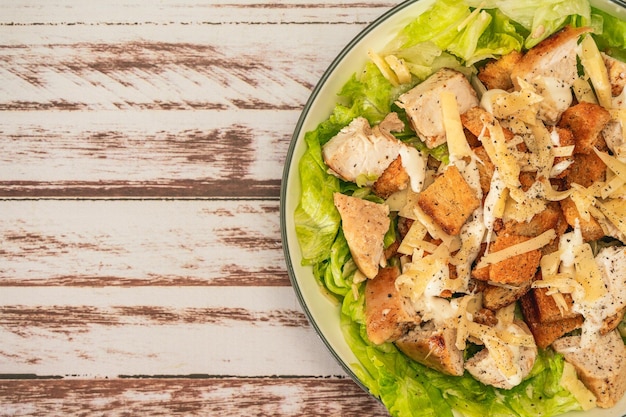 Exquisite Caesar salad with small bites of chicken and a traditional aioli sauce in a small bowl on a rustic table Top view Closeup detail Large Copy space