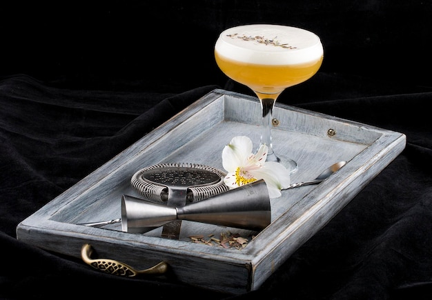 Exquisite cocktail in a glass on a wooden Board Dark background Bartender accessories