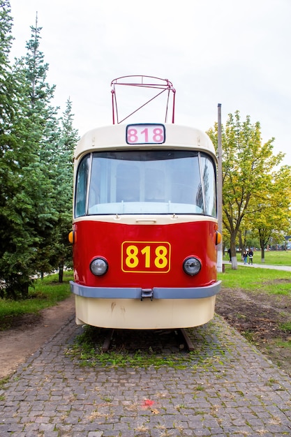 Photo exterior of a vintage red and white tram on railway as an exhibit with 818 number on it, greenery around, chisinau, moldova