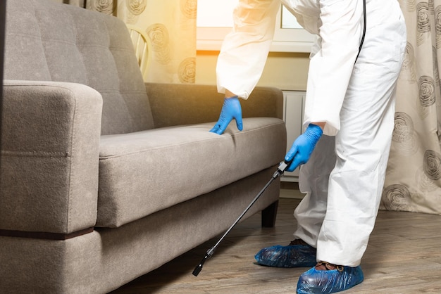 An exterminator in work clothes sprays pesticides from a spray bottle Fight against insects in apartments and houses Disinsection of premises