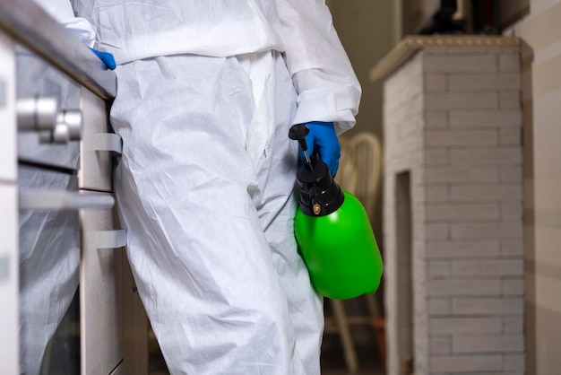 An exterminator in work clothes sprays pesticides with a spray gun Fight against insects in apartments and houses Disinsection of the premises