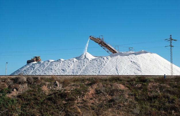 Extraction of salt and pouring it into one big heap with the help of equipment.