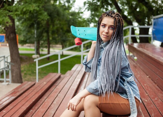 Extraordinary woman skater with afrobraids skateboard sits on the podium