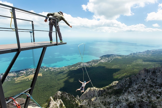 Extreme athlete tied to a safety rope jumped into the void from a mountain rear view Ropejumping