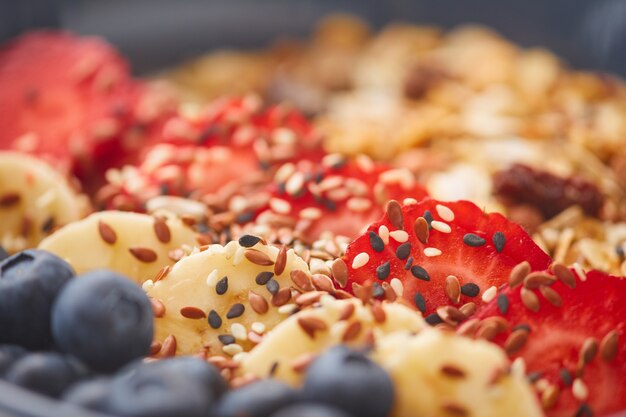 Extreme close up of delicious granola dessert decorated with fruit and berries with sesame seeds, healthy breakfast concept