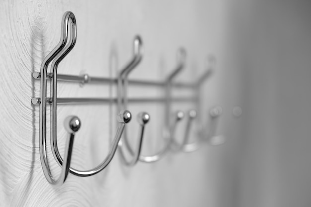 Extremely closeup metal coat hooks on white wall selective focus