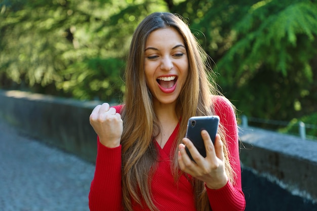 Exuberant young woman cheering at good news on her mobile phone