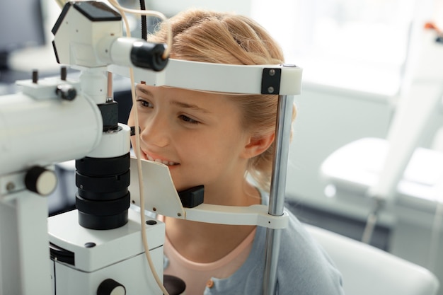 Eye clinic. Beautiful dark-eyed blonde girl wearing blue sweater coming to private eye clinic