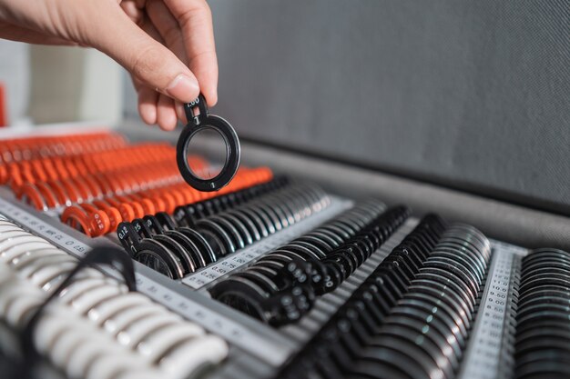 An eye doctor's hand is taking a test glasses lens gauge in a box containing a set of lenses in an eye clinic