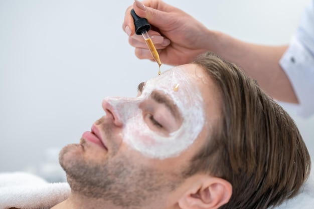 Eye mask. Professional cosmetologist applying hydrating mask on mans eye area