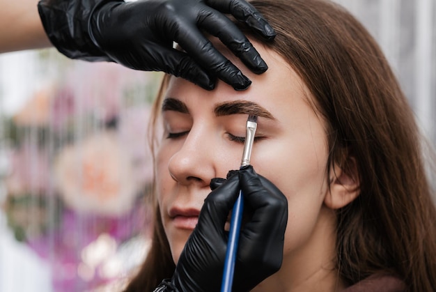 Eyebrow coloring Closeup the master applies paint to the eyebrow with a brush