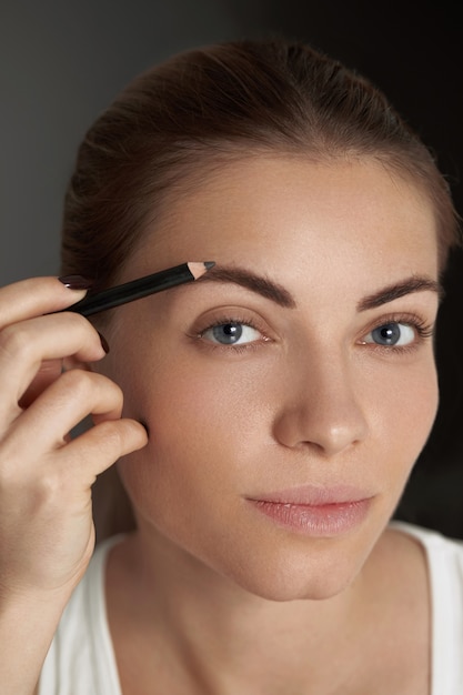 Eyebrow makeup. Beauty model shaping brows with brow pencil