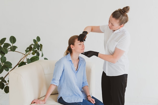 Eyebrow master, beautician corrects the eyebrows of a young woman