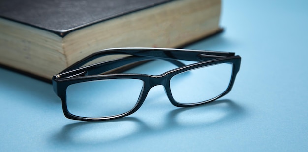 Eyeglasses and book on the blue background