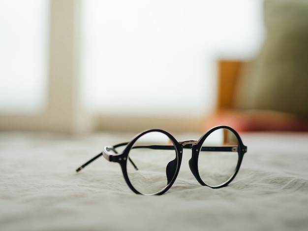 Eyeglasses on white bed in the morning.