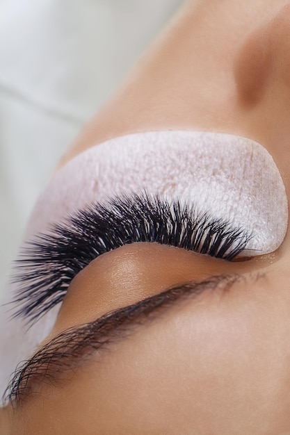 Eyelash extension procedure woman eye with long blue eyelashes ombre effect close up selective focus