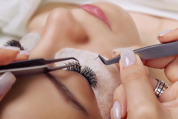 Eyelash extension procedure woman eye with long blue eyelashes ombre effect close up selective focus