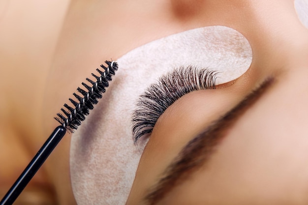 Eyelash extension procedure woman eye with long blue eyelashes ombre effect close up selective focus