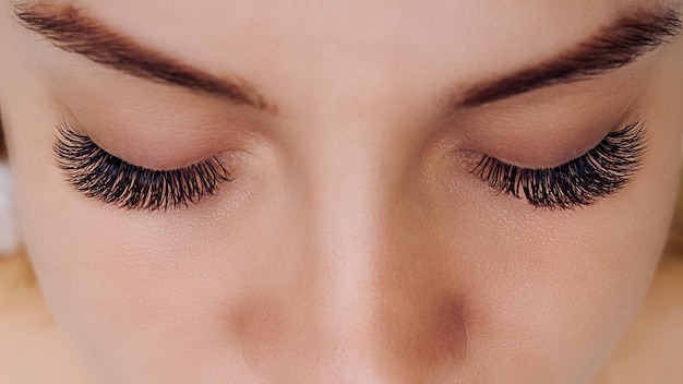 Eyelash extension procedure woman eye with long blue eyelashes ombre effect close up selective focus