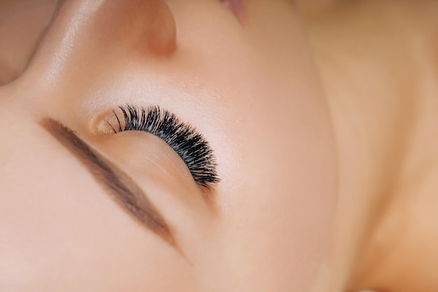 Eyelash extension procedure woman eye with long eyelashes close up selective focus